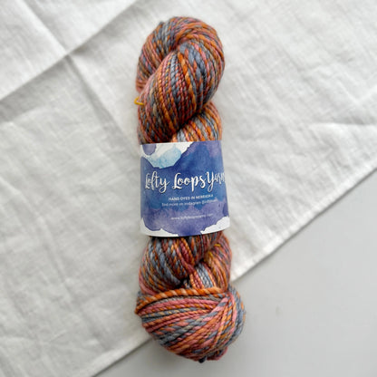 Multicolored skein of yarn with a label on a textured white background