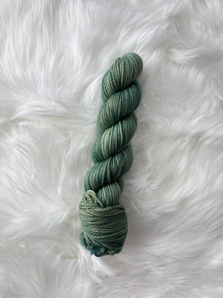 Green skein of yarn on a white fluffy surface
