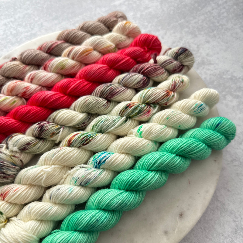 Colorful yarn skeins on a white plate against a light gray background