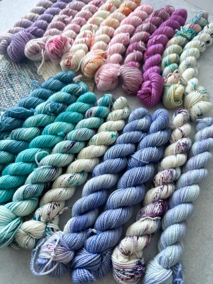 Assorted skeins of colorful yarn in various shades on a textured surface.