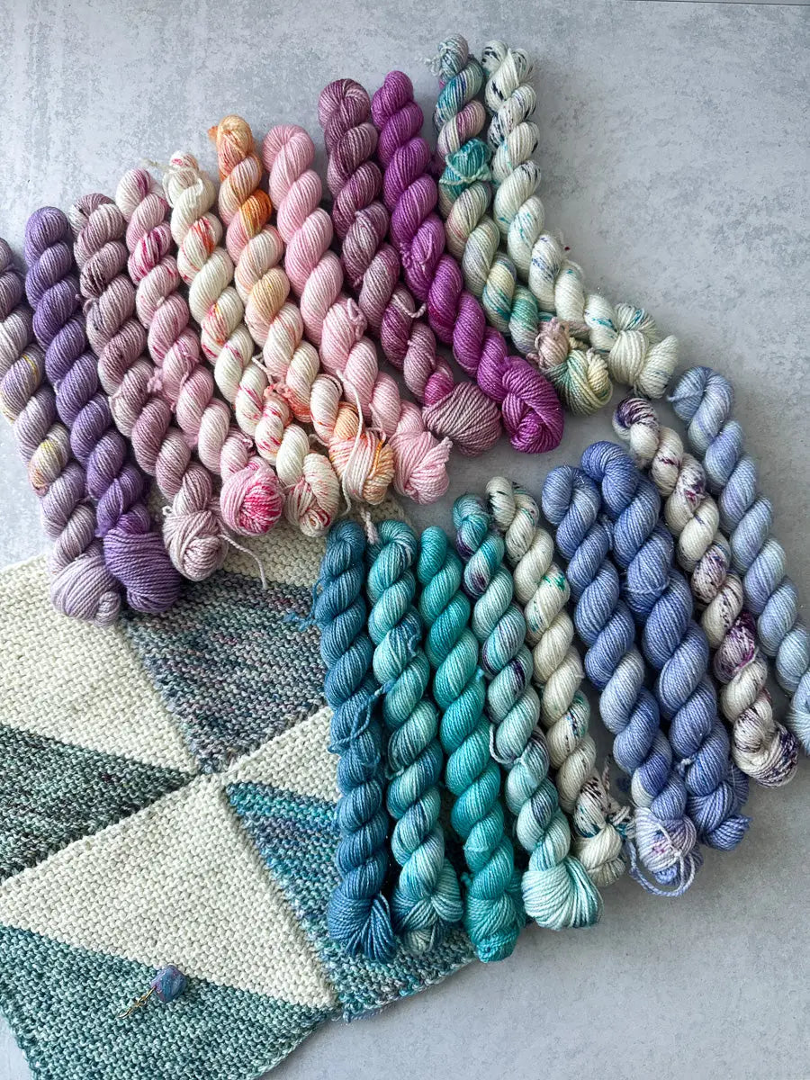 Colorful yarn skeins arranged in a fan shape on a textured surface.