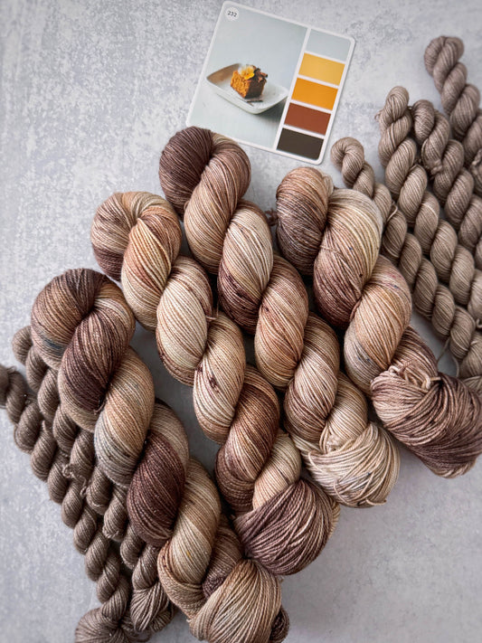Bundles of brown and beige yarn with a color swatch on a light gray background