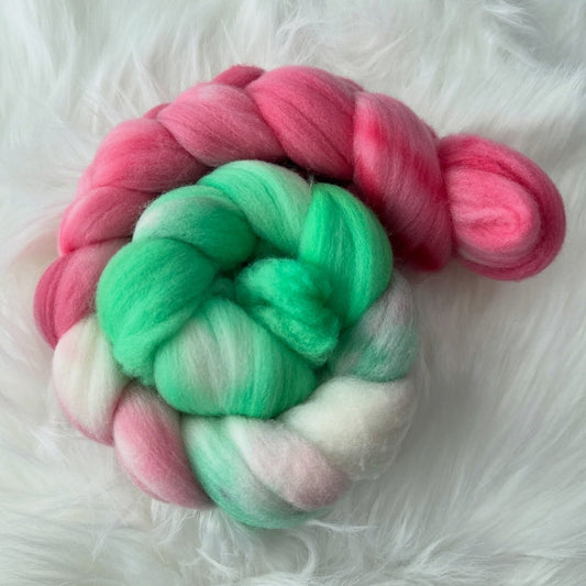 Braided pink, green, and white yarn on a fluffy white surface